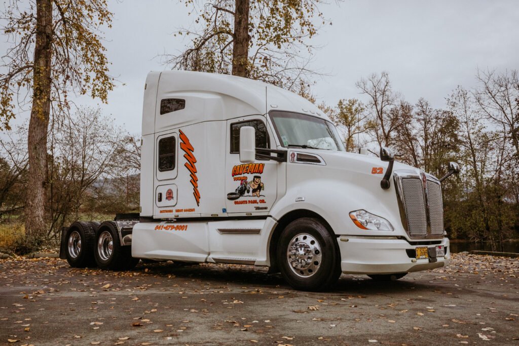 Heavy-duty Caveman Towing semi truck parked in Southern Oregon with clean white cab and company logo, ready for professional heavy vehicle towing and transport
