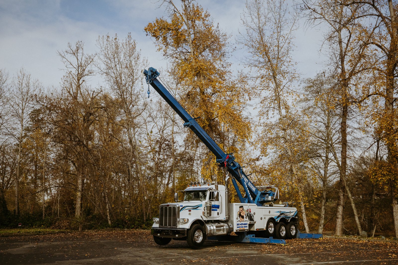 Heavy-duty tow truck with extended boom parked on a paved lot in Southern Oregon, ready for 24/7 recovery and commercial towing services.